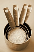 Measuring cups of different sizes with flour