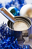 Various measuring cups with flour and Christmas decorations