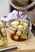 Sweet & sour pickled onions: pouring vinegar onto onions in jar