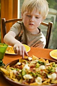 Junge isst Nachos mit Tomatensalsa und Guacamole