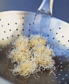 Fish balls in glass noodle coating, unfried on perforated wok