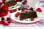 Two pieces of cherry cake with cherries and rose petals