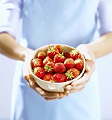 Woman holding a small bowl of fresh strawberries