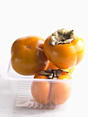 Four Sharon fruits in a plastic container