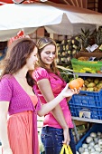 Zwei junge Frauen beim Einkaufen vor einem Obststand