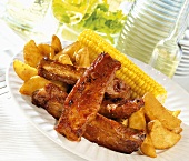 Spare-ribs with potato wedges and corn on the cob