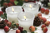 Frostige Gläser mit Kerzen, Zieräpfel, Zapfen und Weissdorn