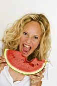 Blonde Frau beisst wild entschlossen in eine Melonenspalte