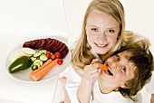 Two children snacking on fresh vegetables