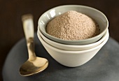Cocoa powder in a small bowl on a pile of bowls