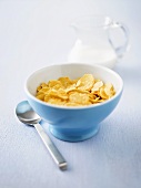 Cornflakes in a bowl and jug of milk