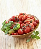Various types of tomatoes in a bowl with basil