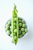 Fresh peas and a pea pod in a dish
