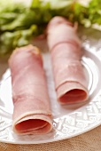 Ham rolls on a plate with salad leaves