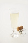 A glass of sparkling wine with cork in background
