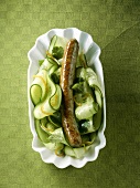 A sausage on cucumber salad