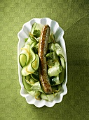 Eine Bratwurst auf Gurkensalat