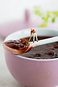 A little toy man on a spoonful of strawberry jam