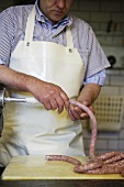 Butcher filling sausage skins with sausagemeat
