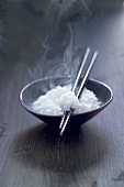 Cooked rice in small bowl with chopsticks