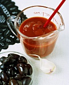 Tomato purée in measuring jug with olives and garlic