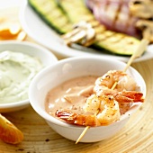Scampi on skewer on small bowl of cocktail sauce