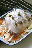 Raw leg of lamb studded with rosemary & garlic in roasting tin