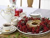 Cake in rowan berry wreath on table laid for coffee
