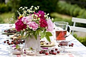 Cherry desserts and vase of flowers on table in garden