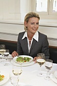 Frau mit elegantem Anzug beim Essen in einem Restaurant