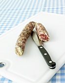 Raw cured sausages, half and whole, with knife