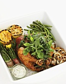 Grilled chicken with herbs, asparagus wrapped in bacon and grilled lemons