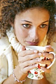 A young woman drinking a hot cup of tea