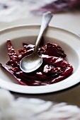A plate of dried red chili peppers with a spoon