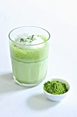 Grüner Tee (aufgeschlagen) im Glas