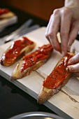 Peppers being placed on bruschetta slices