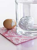 A cracked egg being boiled in tin foil