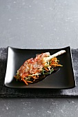 A prawn kebab on a bed of raw vegetables