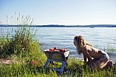 A young woman barbequing by a lake