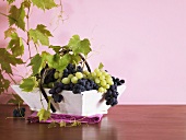 Mixed grapes with vine leaves in a small basket