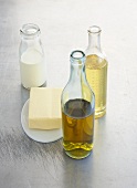Olivenöl, Rapsöl und Milch in Glasflaschen mit Butter