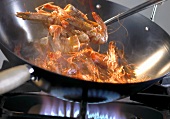 Frying gambas in a wok over a gas flame