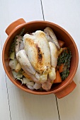 Partly-cooked chicken on vegetables in a stew pot
