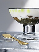 Cauliflower cream on caviar in glass bowl with golden spoon