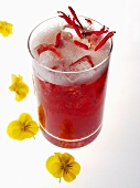 A glass of red iced tea with edible flowers