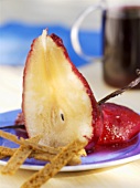 A halved red wine pear with vanilla pod