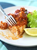Salmon with pepper and tomato sauce and salad leaves