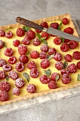 Cheesecake topped with raspberries on a marble slab