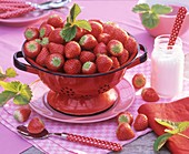 Erdbeeren in einem Küchensieb, Zucker und Löffel