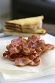 Fried rashers of bacon on kitchen paper, toast